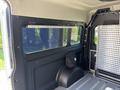 Interior view of a 2022 RAM Promaster 350 showing a large window and a black backpack on the interior wall with a silver panel beside it