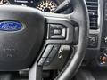 Close-up of the steering wheel controls of a 2015 Ford F-150 featuring buttons for volume playback and cruise control
