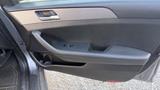 A 2018 Hyundai Sonata car door panel featuring a handle and control buttons for window adjustments