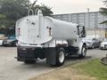 A white 2006 Freightliner M2 106 truck with a large cylindrical tank attached to the back and two exhaust pipes on top