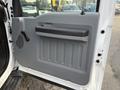 Interior door panel of a 2015 Ford F-350 featuring a gray plastic finish with a textured grip handle and control for window operation