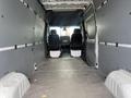 Interior view of a 2025 Mercedes-Benz Sprinter showing the cargo area with two front seats visible and grey paneling on the walls