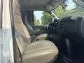 Interior of a 2021 Chevrolet Express showing the driver's seat and dashboard with beige upholstery and controls visible