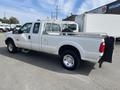 A 2014 Ford F-250 SD pickup truck with a white exterior featuring a bed mounted spare tire and chrome wheels