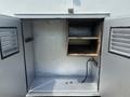 Empty storage compartment of a 2011 Workhorse W62 showing wooden shelves and a black cable on the floor