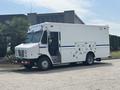 A white 2011 Workhorse W62 delivery truck with a blue stripe and side compartments parked on a pavement