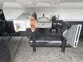 A close-up of a 2006 Freightliner M2 106's air compressor and mounting bracket with a valve and attached pipe system