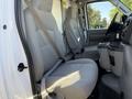 Interior view of a 2021 Ford Econoline showing two gray fabric front seats with seatbelts in place and a center console between them
