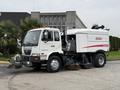 A 2009 UD Trucks UD 3300 street sweeper with a white body and red accents is parked with its sweeping brushes deployed