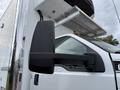 A white 2019 Ford F-750 with a large side mirror and part of a truck bed in the background