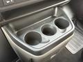 A black cup holder unit with three circular compartments located in the front area of a 2004 Chevrolet Express
