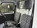 Interior of a 2009 Suzuki Carry with two gray patterned seats and a manual gear shift in the foreground