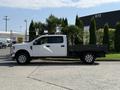 A white 2020 Ford F-350 SD with a flatbed is parked, showcasing its side profile and chrome wheels