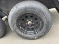 A black tire mounted on a wheel with multiple bolt holes and visible tread wear featuring the brand name Rhoden on the sidewall