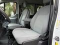 Two gray cloth seats of a 2018 Ford Transit van with armrests in a spacious interior setting