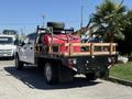 A 2019 Ford F-350 SD truck with a flatbed, featuring a red fuel tank and a spare tire secured at the back