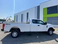 A white 2017 Ford F-250 SD with a flatbed and 4x4 capabilities parked at a commercial site