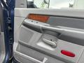 The interior door panel of a 2006 Dodge Ram 2500 featuring wood trim a speaker grille and control buttons for windows and locks