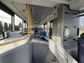 Interior view of a 2016 Grande West Vicinity bus showing a spacious aisle with blue fabric seats and yellow handrails along the walls