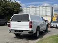 A 2019 Chevrolet Silverado 1500 with a white exterior and truck cap parked at an angle showcasing its rear view and tailgate design