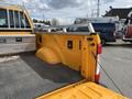 The image shows the bed of a 2017 Ford F-250 SD in bright yellow color featuring a diamond plate toolbox and a curved wheel well on the left side