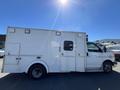 A 2013 Chevrolet Express ambulance with a white exterior and dual entry doors on the side