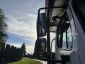 A 2022 Freightliner M2 106 truck with prominent side mirrors reflecting the sky