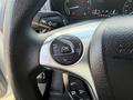 A close-up of the steering wheel controls in a 2021 Ford Transit Connect featuring buttons for navigation and settings