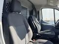 Two black fabric front seats of a 2017 Ford Transit van are shown side by side with visible seatbelts and a dashboard in the background