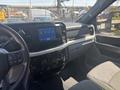 Interior view of a 2023 Ford F-350 SD featuring a touchscreen display and dashboard controls with a gray seat visible in the foreground