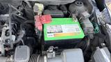 A green battery with red and black terminals inside the engine compartment of a 2019 Nissan Kicks