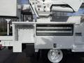 A white 2011 International 4300 utility truck with an extended boom arm and storage compartments on the side