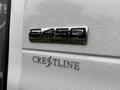 A close-up view of a 2015 Ford Econoline van rear badge featuring the numbers 2450 Super Duty and the Crestline logo above it with droplets of water on the surface
