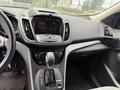 Interior view of a 2015 Ford Escape featuring a central touchscreen display gear shift and control buttons on the console