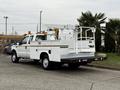 A white 2001 Ford F-350 truck with a utility bed and a cherry picker mounted on the back