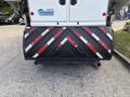 A 2012 International DuraStar 4300 is shown with a large brush attachment at the rear displaying a red and white striped warning pattern