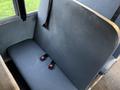 A gray bus seat with two red seatbelt buckles attached