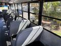 Interior of a 2011 Freightliner B2 school bus featuring gray seats arranged along the sides with a view of large windows and an emergency exit sign