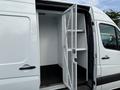 A 2012 Mercedes-Benz Sprinter with an open side door revealing the interior cargo space and shelving inside