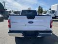 A white 2018 Ford F-150 pickup truck viewed from the rear with a visible Ford logo and model name on the tailgate