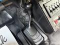 A close-up of the gear shift of a 2008 Ford F-450 featuring a textured black knob and a rectangular base in a black interior