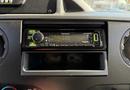 A Kenwood stereo receiver with green and black controls mounted in the dashboard of a 2015 Ford Econoline