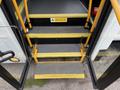 Steps leading up into a 2015 Chevrolet Express with a yellow warning sign to watch your step and grip handles on the sides