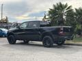 A black 2021 RAM 1500 with a crew cab and oversized black wheels parked at an angle