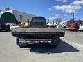 A 1996 GMC Top Kick truck with a wooden flatbed viewed from the rear