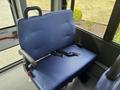 A blue upholstered seat with a safety belt inside a vehicle designed for passenger transport
