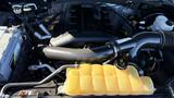 Engine compartment of a 2016 Ford F-150 featuring a black engine cover and yellow coolant reservoir
