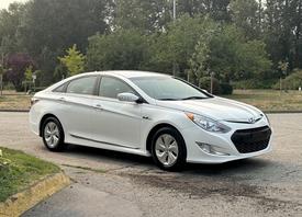 A white 2015 Hyundai Sonata parked with its front angled towards the viewer showcasing a sleek design and modern features