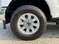 A close-up of a silver alloy wheel with a shiny center cap and black tire tread on a 2021 Ford F-350 SD