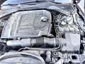Engine compartment of a 2020 Jaguar XE featuring a black engine cover with the Jaguar logo and various components including hoses wires and fluid reservoirs
